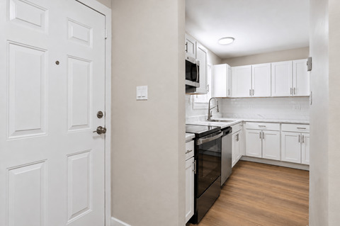 A white door is on the left of a kitchen.