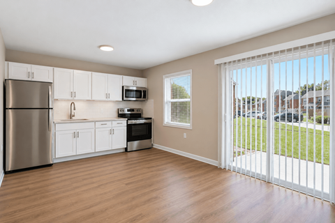A kitchen with white cabinets and a stainless steel refrigerator.