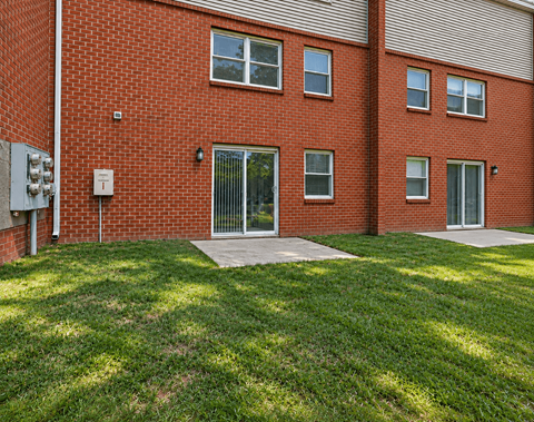 A red brick building with a green lawn in front.