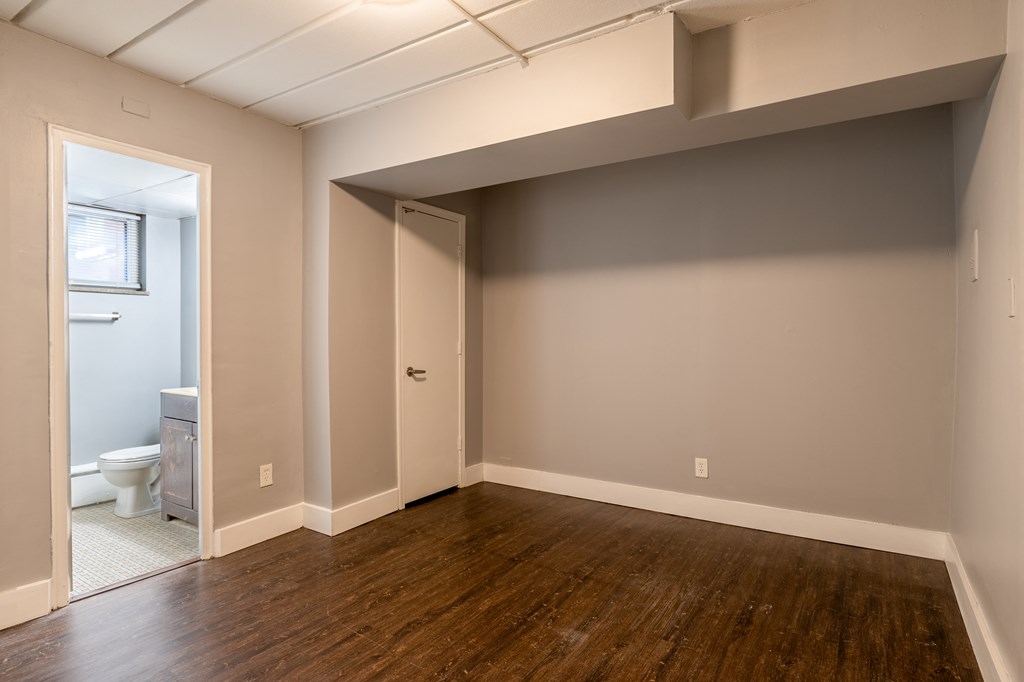 a living room with wood flooring and a door to a bathroom
