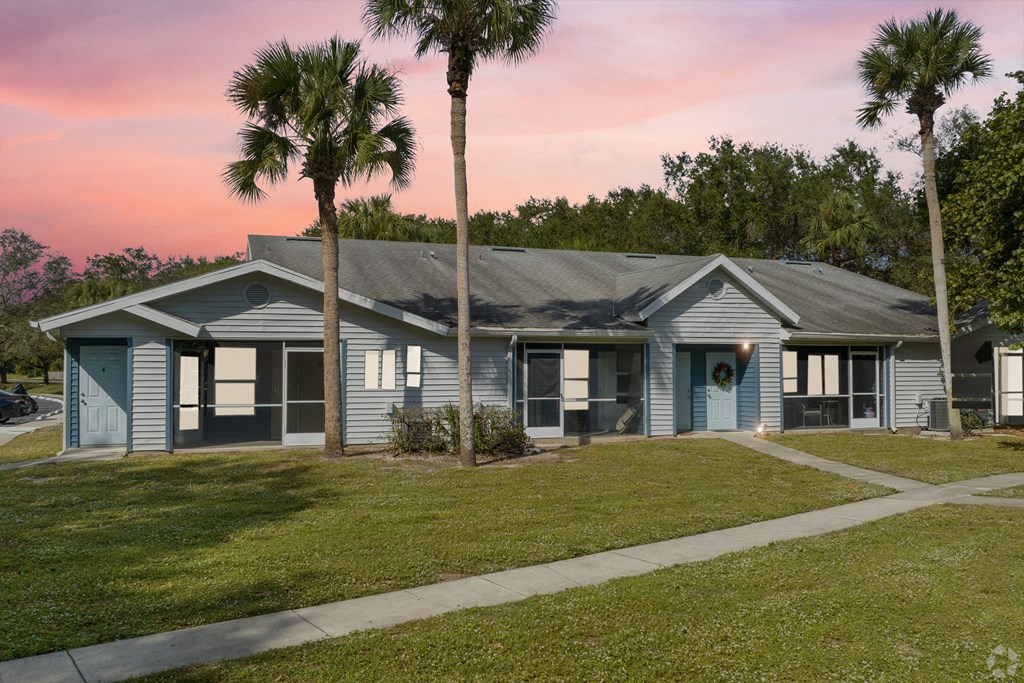 a blue house with palm trees in front of it at Aqua Bay Apartments in Naples, FL 34116