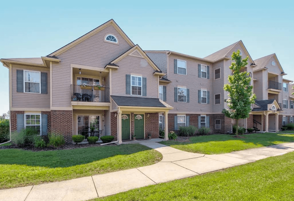 A large, multi-story apartment building with a green lawn in front.