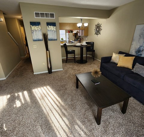 A living room with a couch, coffee table, and a dining table with chairs.