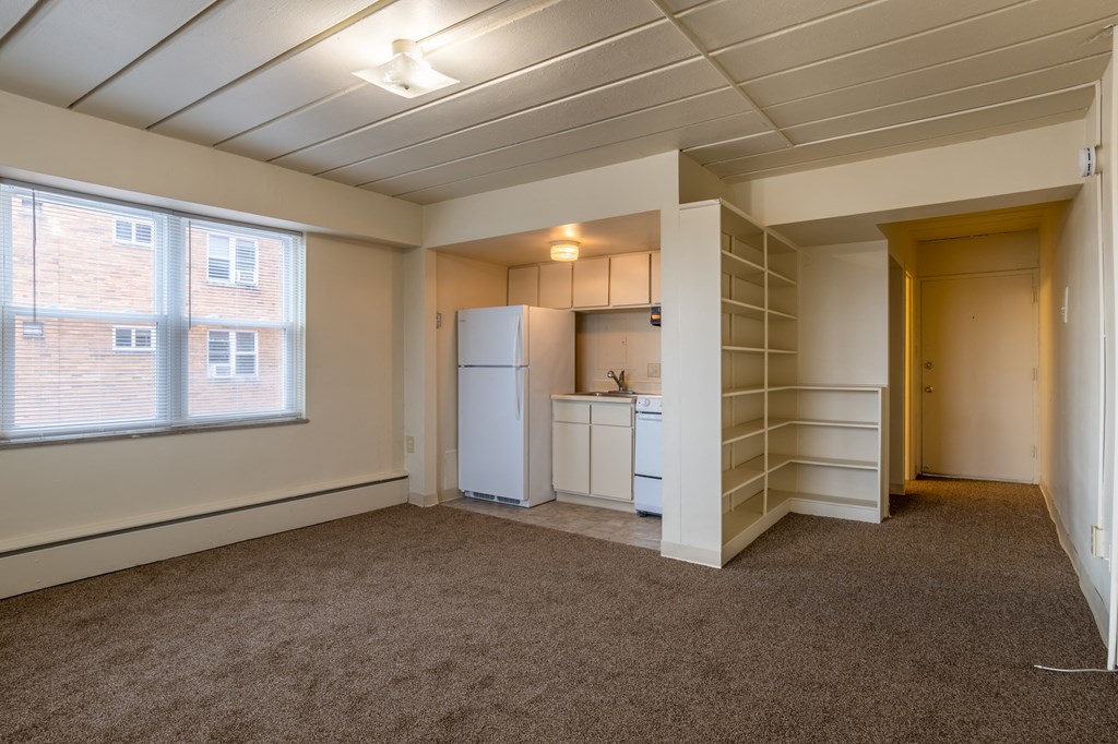 an empty room with a kitchen and a window