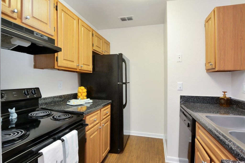 A kitchen with wood cabinets and black appliances at Aqua Bay Apartments in Naples, FL 34116