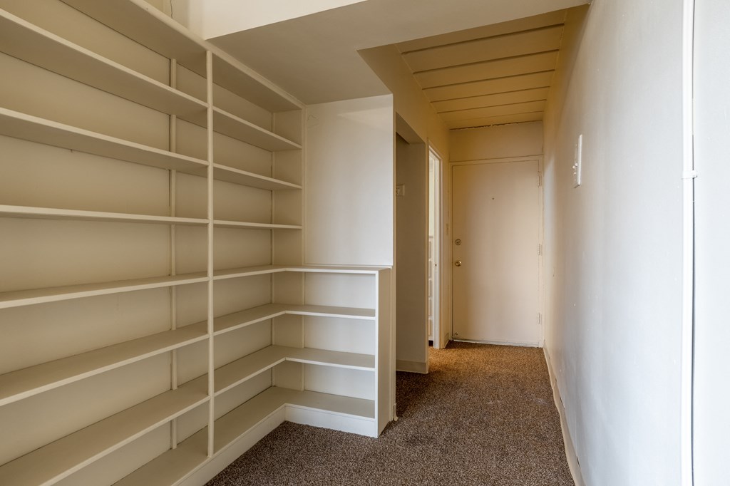 a walk in closet in a house with empty shelves