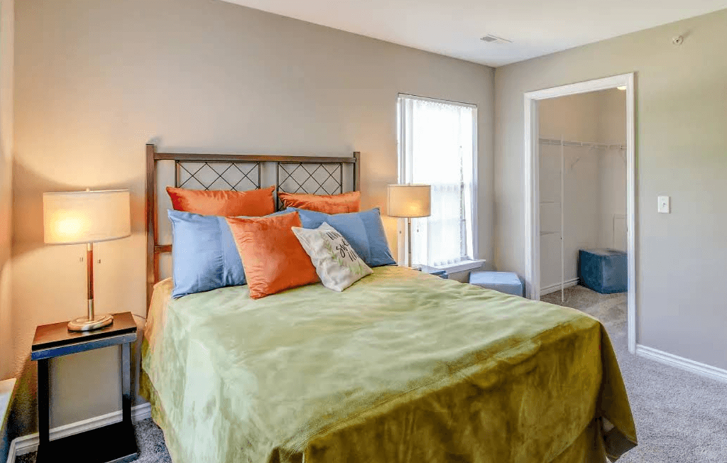 A bedroom with a bed, nightstand, and window.