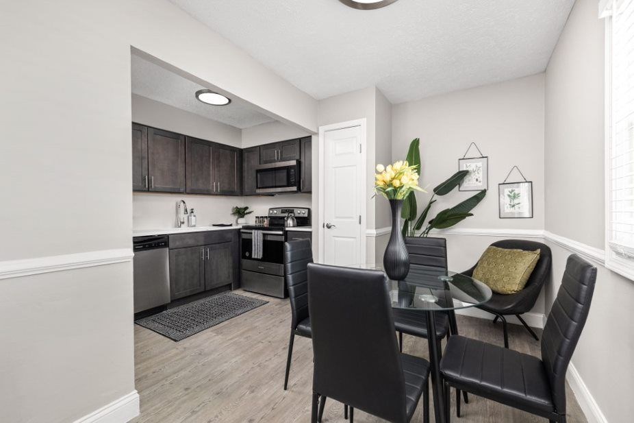 a dining area with a table and chairs and a kitchen in the background