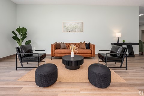 A living room with a brown sofa, black chairs, and a coffee table.