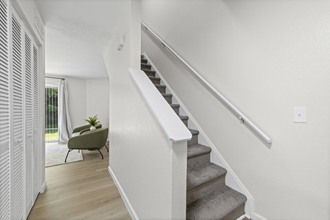 A staircase with a white railing and a green chair with a plant on it.