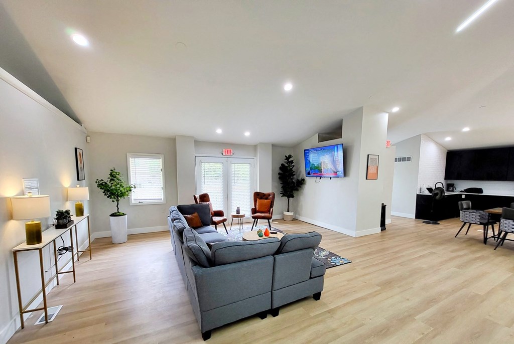 a living room with a couch a table and chairs and a flat screen tv on the wall