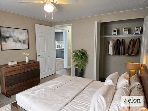 A bedroom with a bed, dresser, and coat rack.