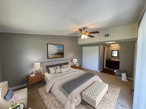 A bedroom with a large bed and a ceiling fan.