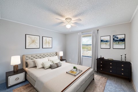 A bedroom with a large bed, a dresser, and a ceiling fan.