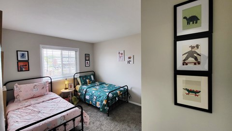 A bedroom with two beds and a wall of framed pictures.