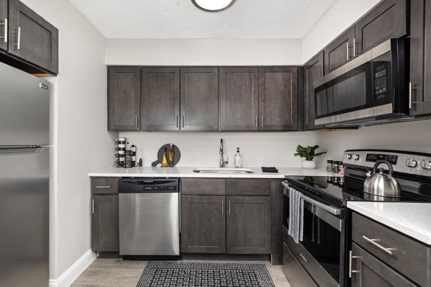 a kitchen with dark cabinets and stainless steel appliances