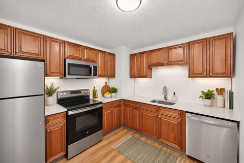 A kitchen with wooden cabinets and a stainless steel refrigerator.