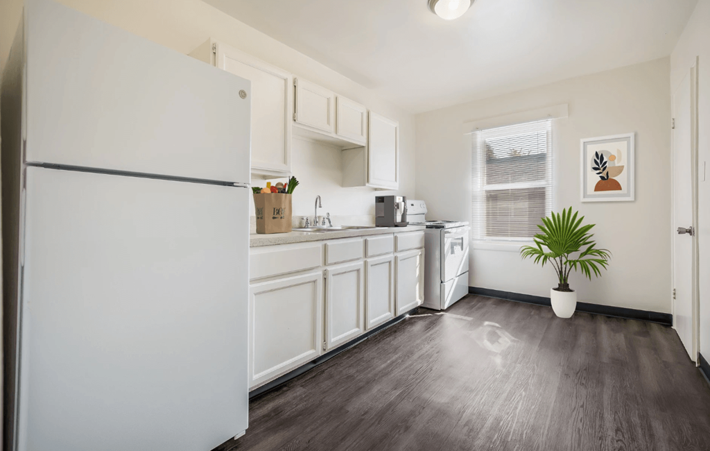 a white kitchen with white cabinets and a white refrigerator