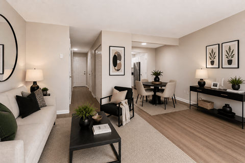 A living room with a white couch, a black coffee table, and a dining area with a table and chairs.