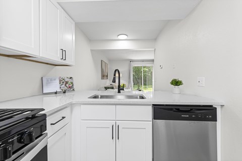 A kitchen with white cabinets and a black stove top.