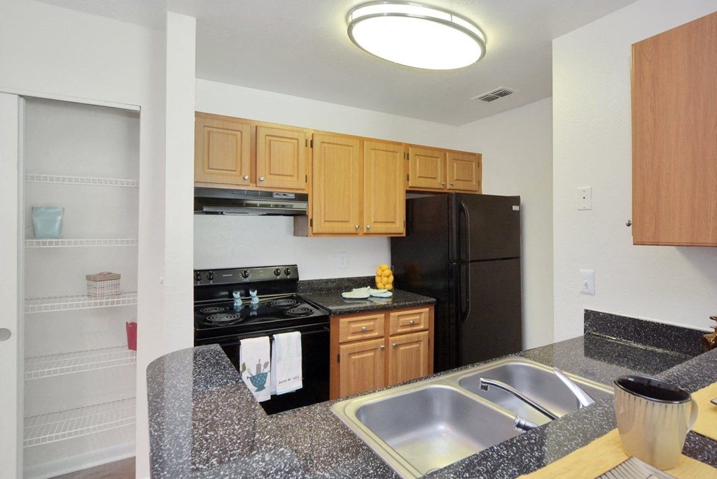 A kitchen with granite countertops and black appliances at Aqua Bay Apartments in Naples, FL 34116