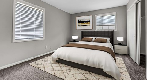 A bedroom with a large bed and a rug on the floor.