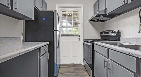 A kitchen with a black fridge and a white door.