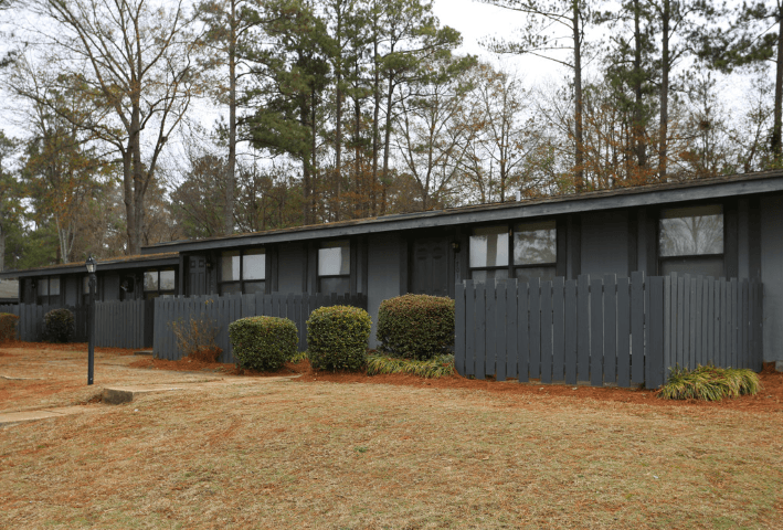 the exterior of a black house with a yard and trees