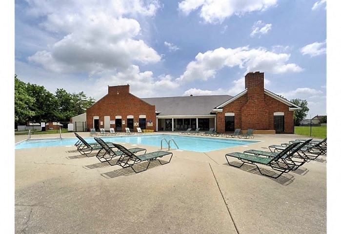 Outdoor pool area with several lounge chairs surrounding the pool. 