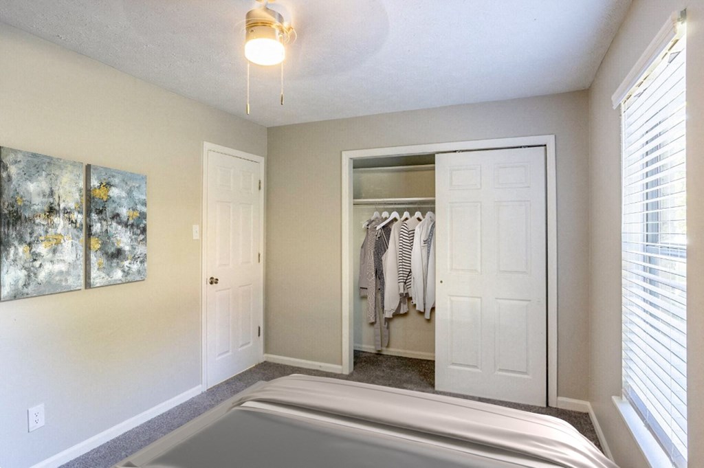 an empty bedroom with a closet with a bed and a window