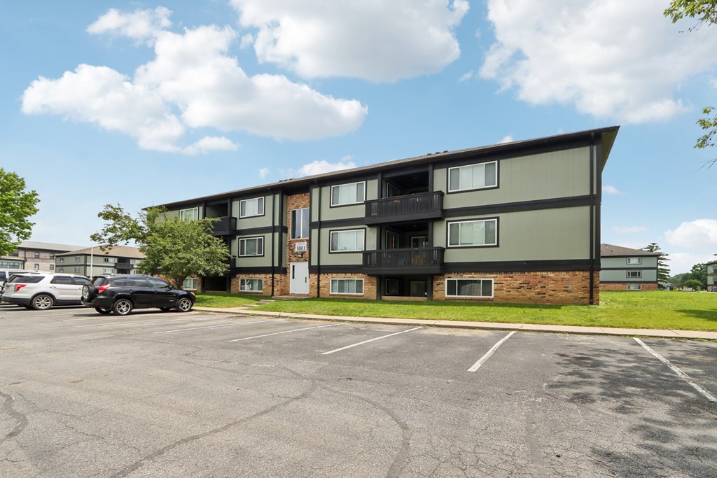 A parking lot in front of a multi-story apartment building.