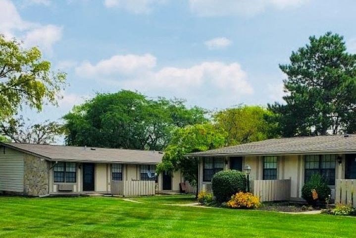 a row of houses with a green lawn and trees