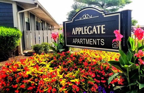 a sign in front of a garden of flowers