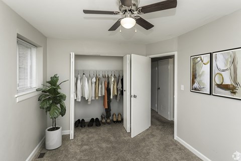 a bedroom with a ceiling fan and a closet with a plant in it