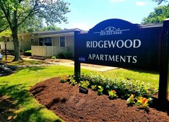 a sign for ridgewood apartments in front of a garden