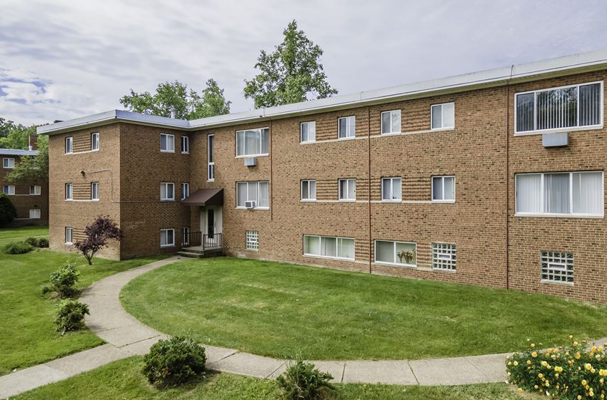 a large brick building with a green lawn in front of it - Photo Gallery