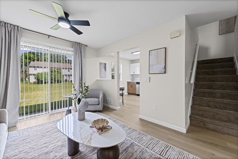 A living room with a fan, a sofa, a table and a staircase.