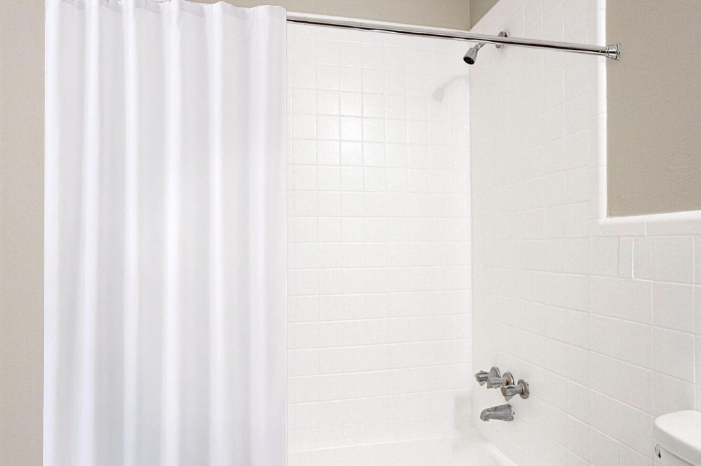a white bathroom with a shower curtain and a toilet