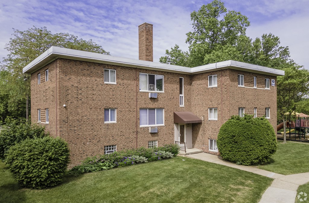 a brick building with a chimney and a green lawn