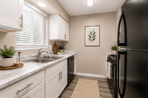 A kitchen with white cabinets and a black refrigerator.