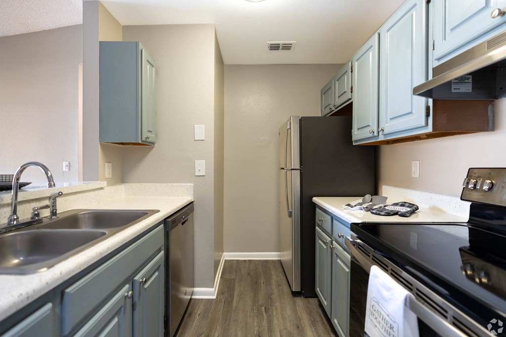 a kitchen with stainless steel appliances and blue cabinets at Aqua Bay Apartments in Naples, FL 34116