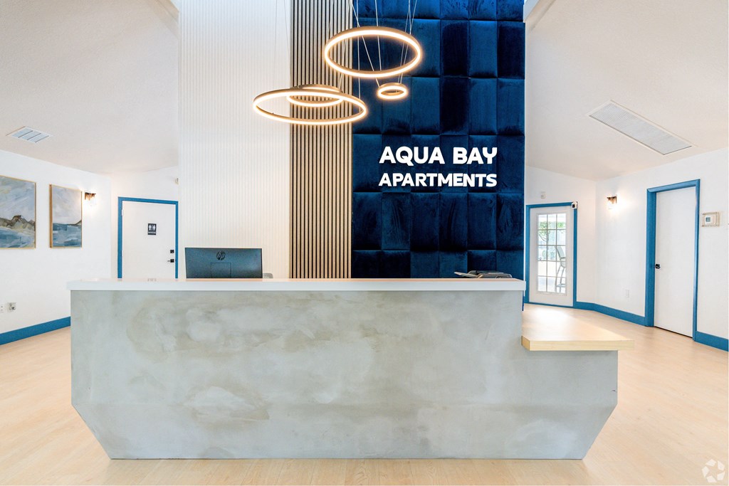 the front desk apartments with a marble reception desk and a sign at Aqua Bay Apartments in Naples, FL 34116