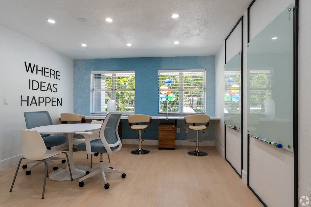 a conference room with a table and chairs and a window at Aqua Bay Apartments in Naples, FL 34116