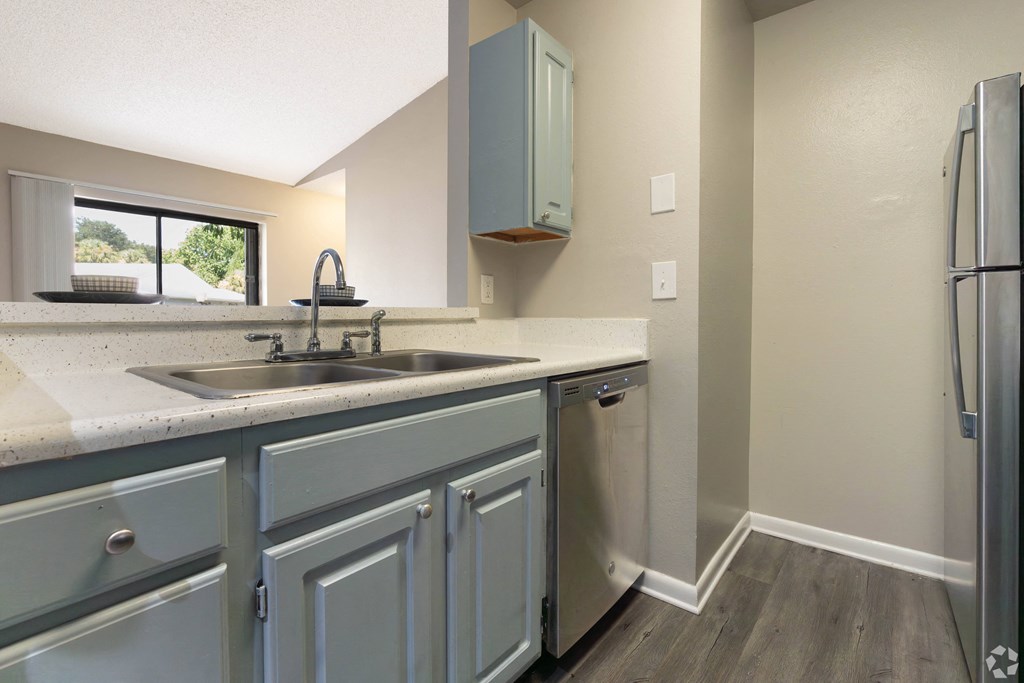 the kitchen of a home with stainless steel appliances and blue cabinets at Aqua Bay Apartments in Naples, FL 34116