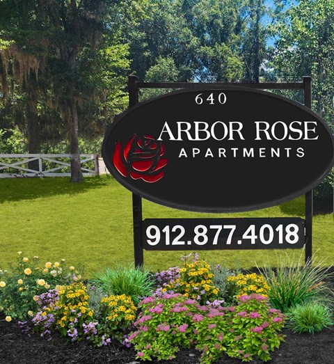 a sign for arbor rose apartments in front of a garden