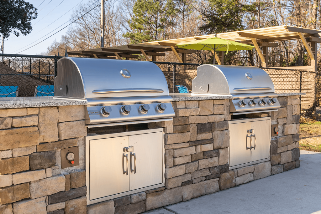 A wall of outdoor grills is built into a stone wall.