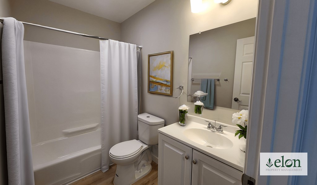 A white bathroom with a toilet, sink, and shower.
