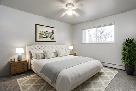 A bedroom with a large bed, a ceiling fan, and a potted plant.