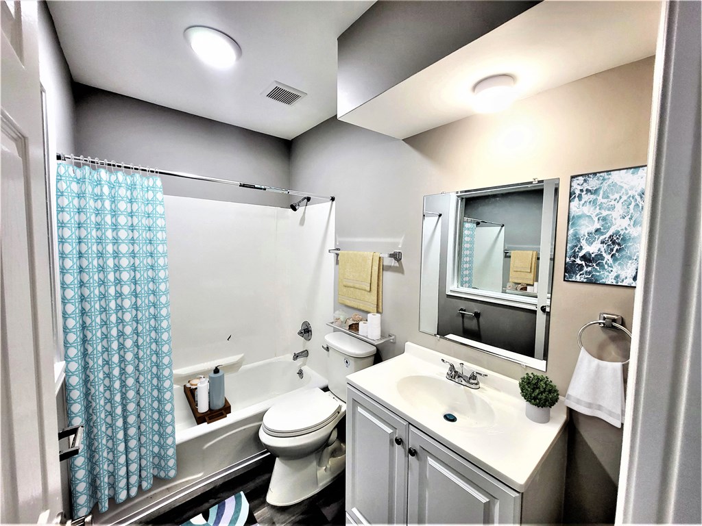 a bathroom with a white toilet next to a tub with a shower curtain