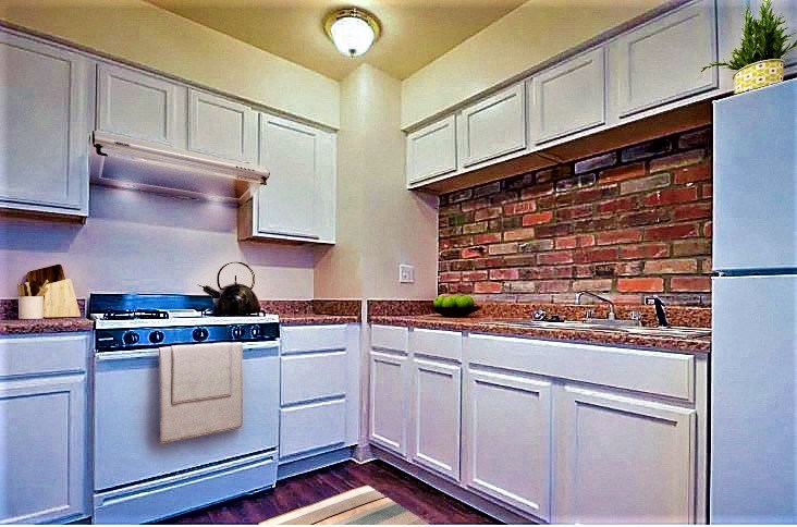 a kitchen with white cabinets and a brick wall
